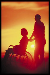 Person in wheelchair pushed by caregiver at sunset