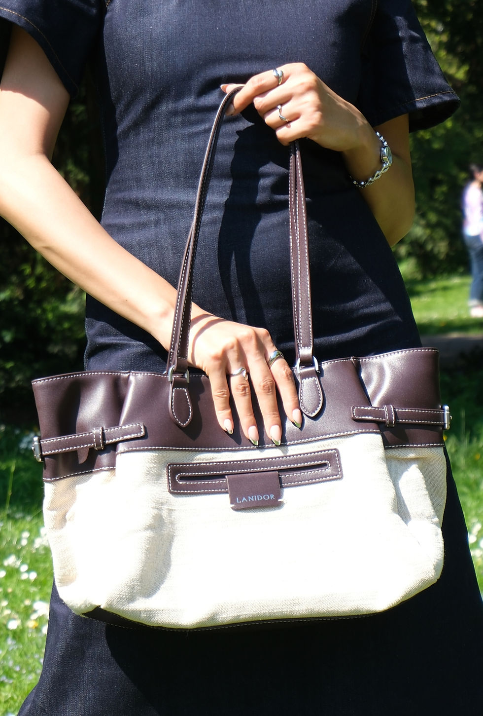 Woman's hands holding a cream and chocolate brown bag