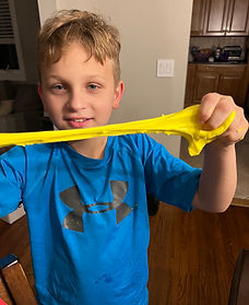 A boy playing and stretching yellow slime at a slime party