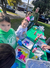 Girl Scouts smiling while making colorful spiral tie-dye T-shirts at an outdoor girl scout park event