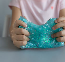 Hands playing with sparkly blue slime