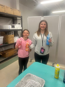 Two girls proudly holding up their tie dye creations at a bring your children to work day event in Central New Hersey