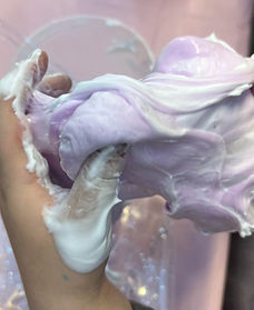 Hands stretching fluffy slime mixed with shaving cream during a kids' craft activity