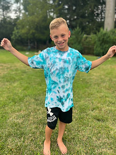 Boy modeling a teal and blue tie dye shirt that he created at a tie dye party