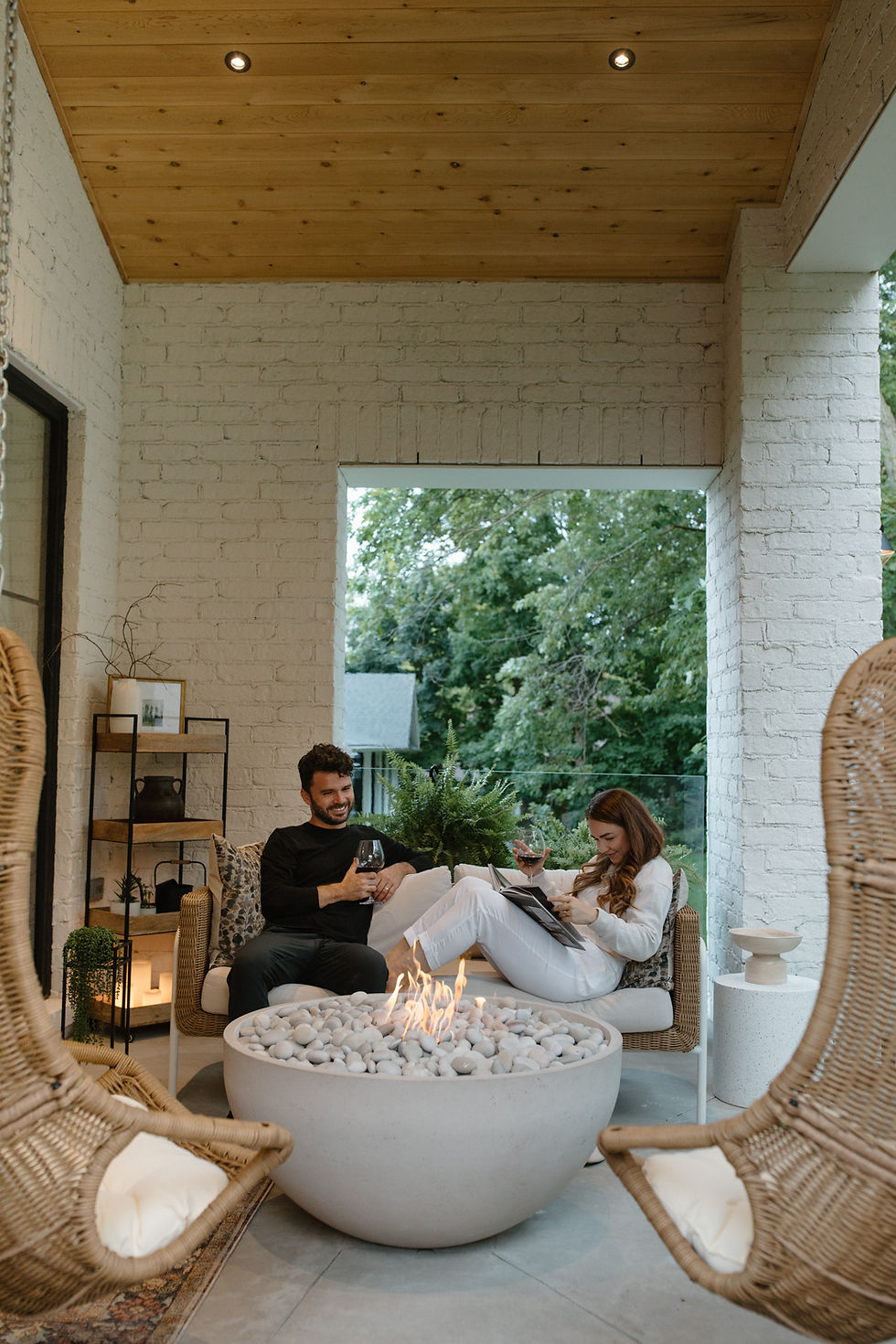 Hillside House Design + Build owners sitting outside talking infront of a fire and smiling.