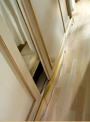 Dettaglio apertura anta centrale bombata dell'armadio laccato e decorato a mano con cornici in foglia oro