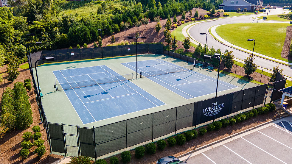 Aerial view of empty blue tennis courts at The Overlook at Old Atlanta. Surrounded by green trees and a clear, sunny environment.