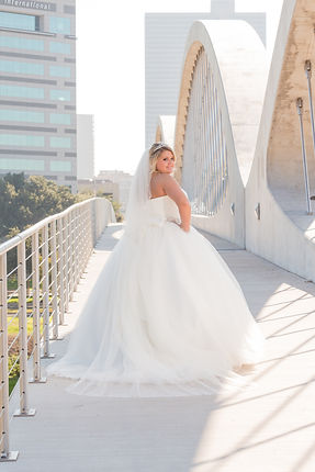 Beautiful bride, looking back, on 7th Street Bridge, with downtown skyline. Crossroads Photography.