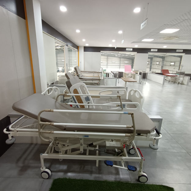 Adjustable hospital bed with side rails and wheels in a modern healthcare showroom.