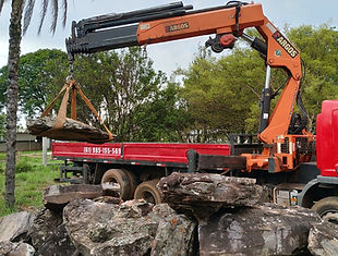 Caminhão munck erguendo pedras pesadas para projetos de paisagismo
