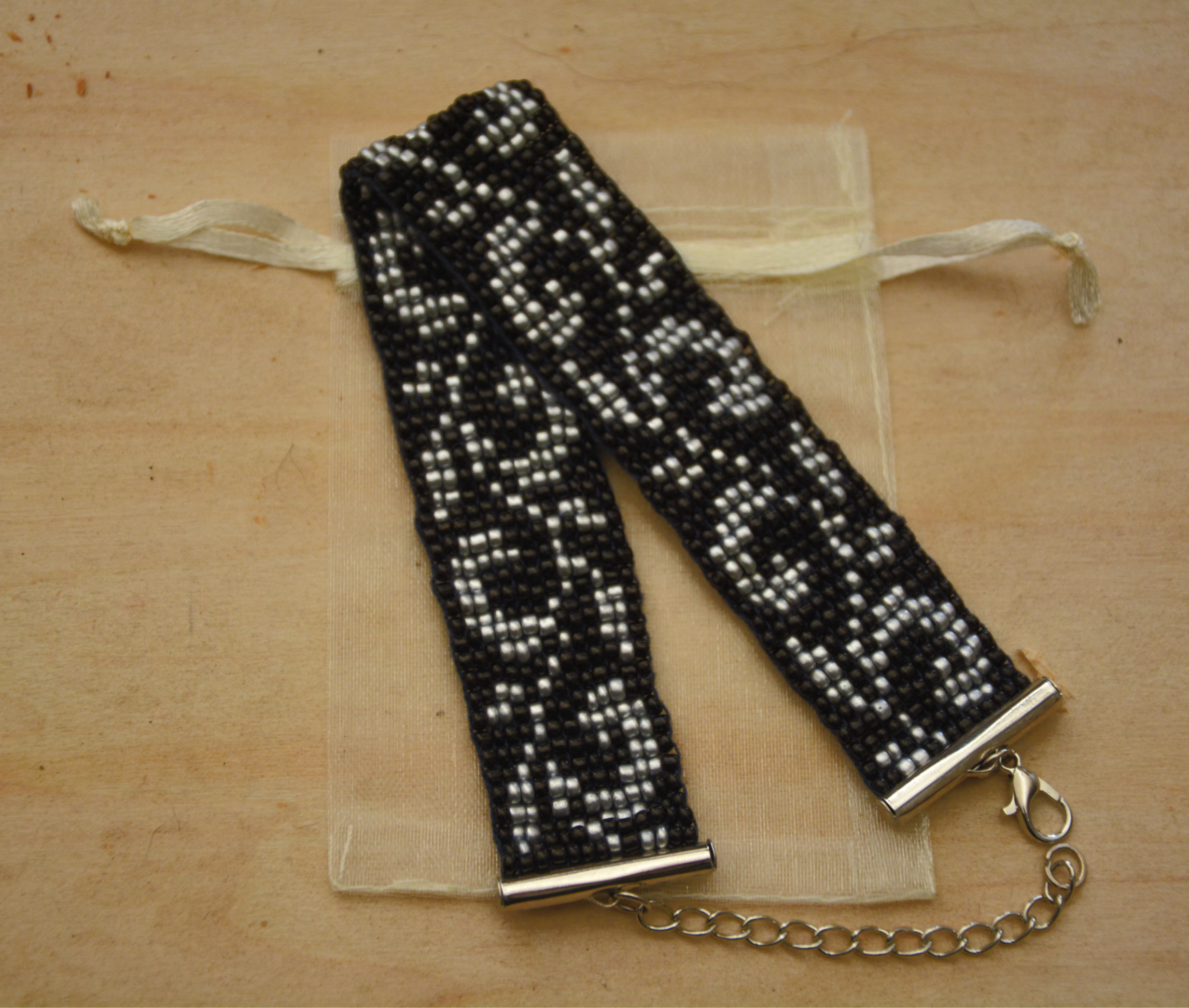 Seed Beads Armband gewebt nickelfrei – schwarz silber geometrisches Muster, 2cm breit, Schiebeverschluss, Organzasäckchen