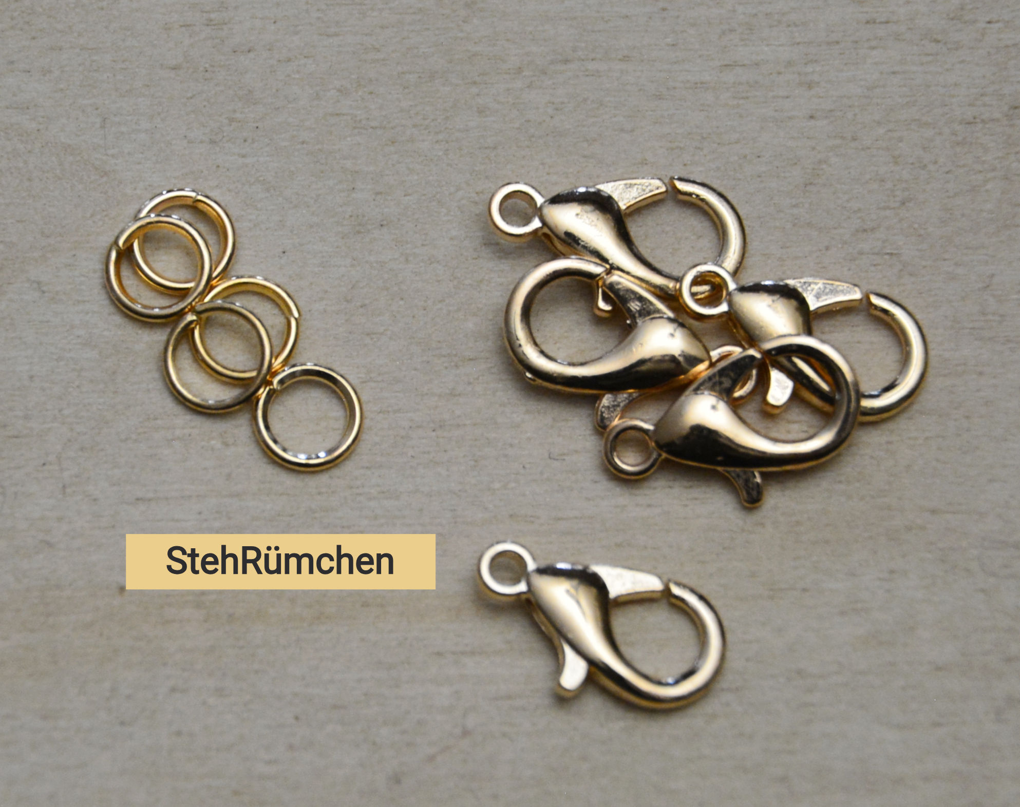 Karabinerverschluss nickelfrei gold 5er Set mit Biegerings auf hellem Untergrund