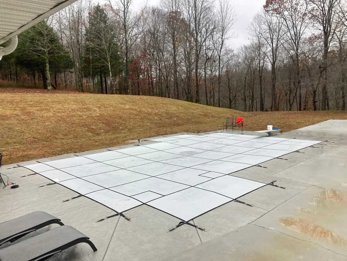 grey safety pool cover protecting the pool from the elements.