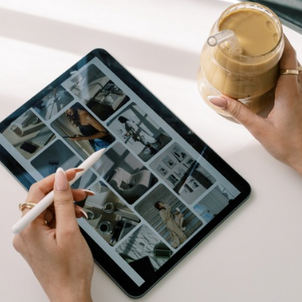 Interior design inspiration board displayed on a tablet with a stylus and iced coffee on a minimalist desk.