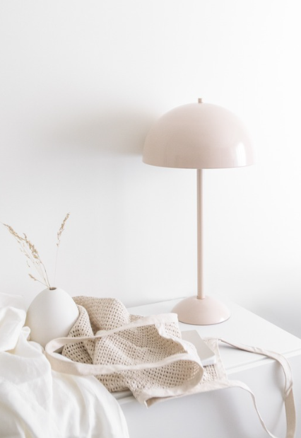 Neutral bedroom styling with table lamp, ceramic vase, and soft textured linens.