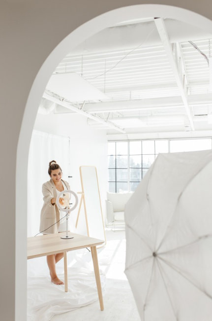 Content creator preparing lighting setup in a minimal, light-filled photography studio.
