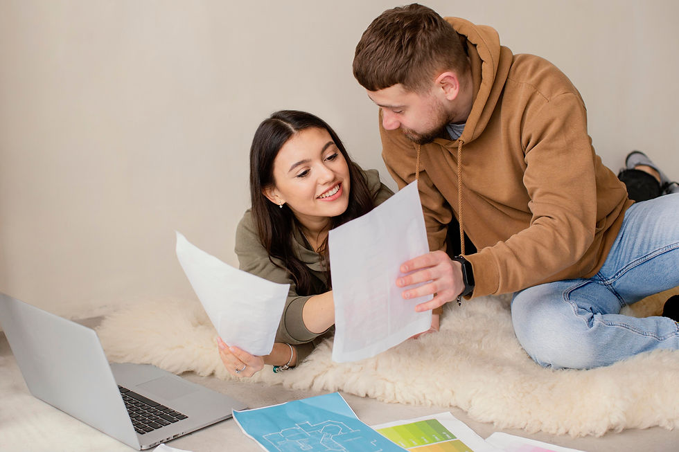 Smiling couple comfortably comparing loan offers on their living room floor.
