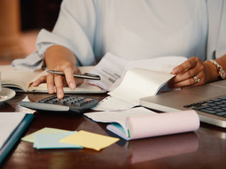 Well-to-do woman at cluttered desk, using a calculator to understand her credit score in Australia 