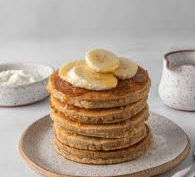 Eye-level view of a stack of protein pancakes topped with fresh berries and honey
