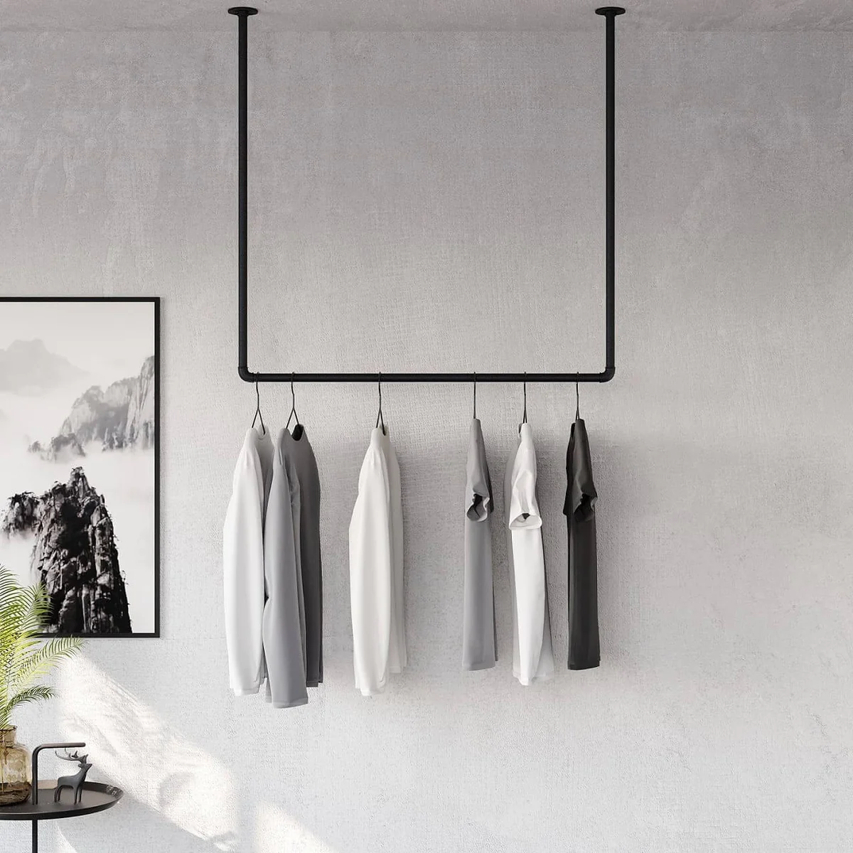 a clothing rack hanging from the ceiling with grey, white and black tshirts hanging from it
