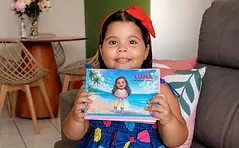 menina segurando livro com sua historia e da sua familia fabulas da vida.webp
