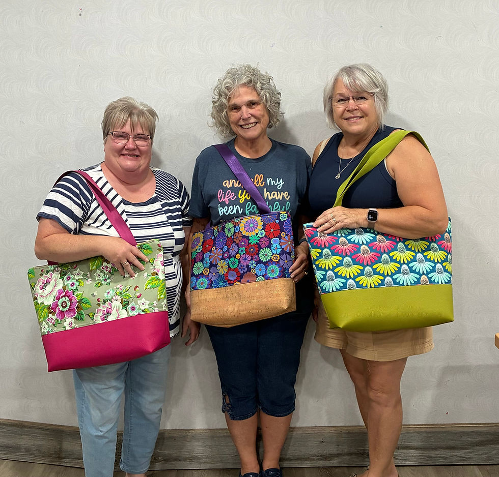 Three women displaying purses they created