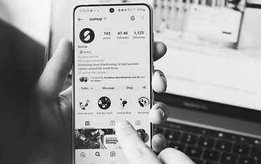 Hand holding phone showing social media content on Brand Babes branded interface