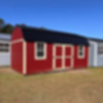 Exterior view of the 10x20 red side lofted barn with a black metal roof, centered double doors, and two windows.