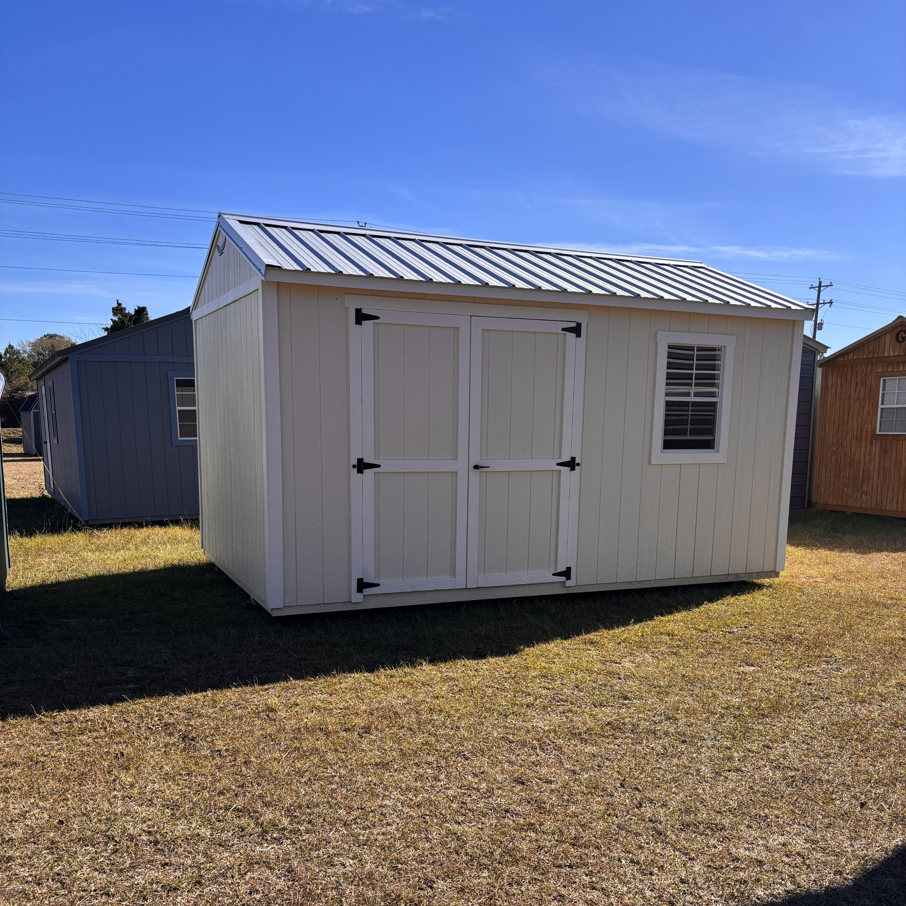 Angled front exterior of the 10x16 utility shed with Navajo white siding and double doors.