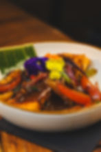 Richly sauced dish with peppers and edible flowers