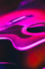 Acoustic guitar glowing in vibrant pink and purple lights
