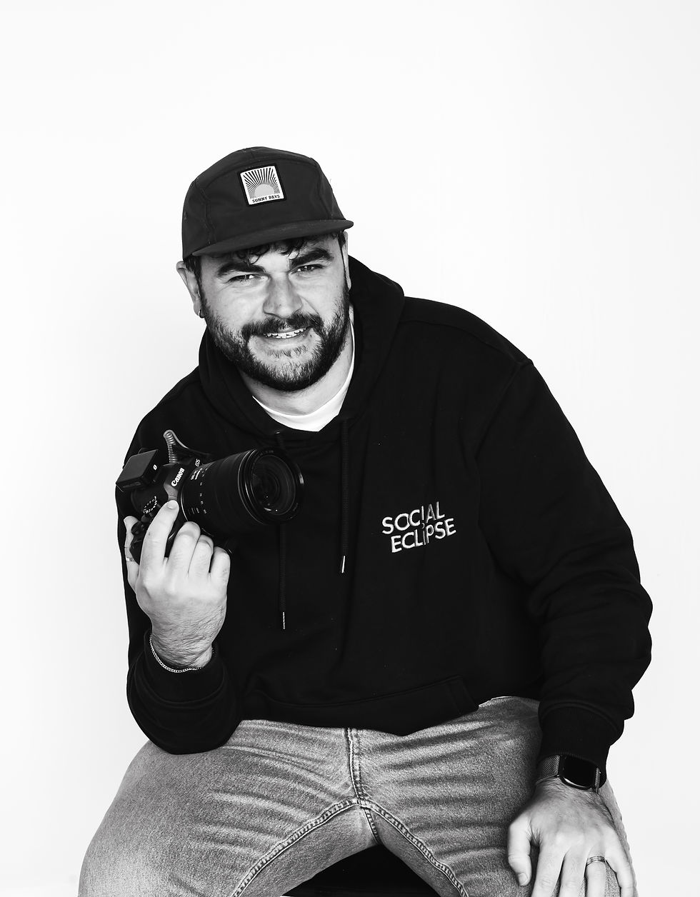 professional portrait photo of tom holding a canon camera wearing a branded social eclipse hoodie