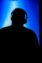 Person in silhouette wearing headphones with blue light
