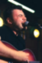 Man singing passionately into microphone, playing guitar