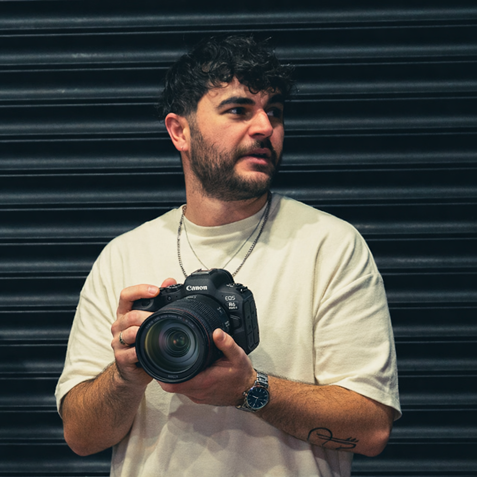 Image of tom holding a canon camera in front of a black shutter