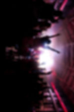 Concert crowd with arms raised towards bright stage lights