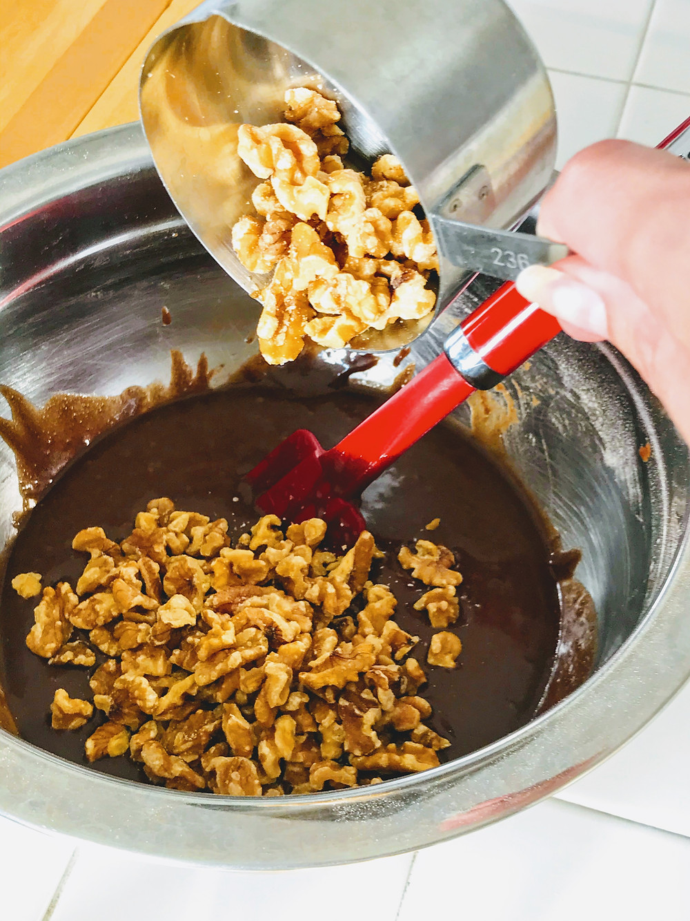 walnuts being poured into brownie batter
