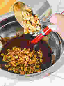 walnuts being poured into brownie batter