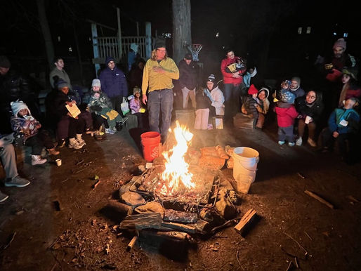 Preschoolers and Parents Gathered around a camp fire.