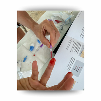 Person pricking a bloodied fingertip with a lancet over an instruction sheet on a white table, with medical tools nearby.