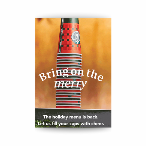 Stack of festive red and green Starbucks holiday cups with the text ‘Bring on the merry’ and a banner reading ‘The holiday menu is back. Let us fill your cups with cheer.’