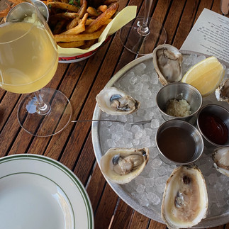 stock photo of oysters and orange wine sitting on a wooden table