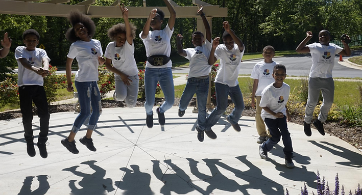 Young people jump together in celebration during a SHIELD Mentor Program activity, reflecting joy, confidence, and connection