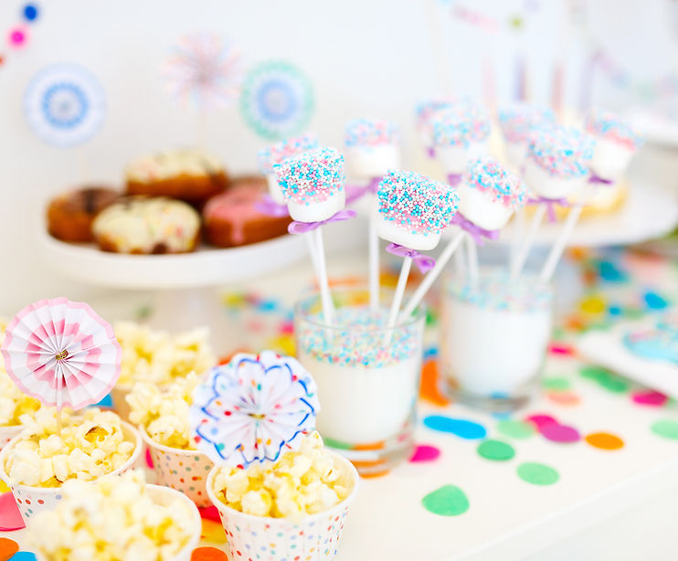 A table of pary food with a brightly coloured table cloth