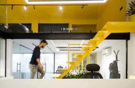 a man walking down a yellow staircase in an office