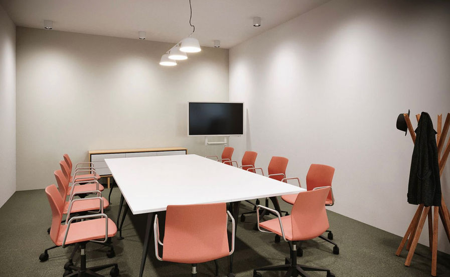 a conference room with a long white table and orange chairs