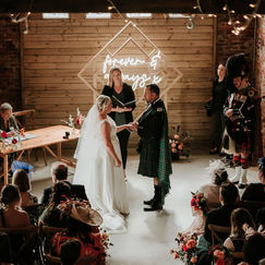 Aerial shot of bride and groom exchanging vows in front of guests at a barn wedding venue