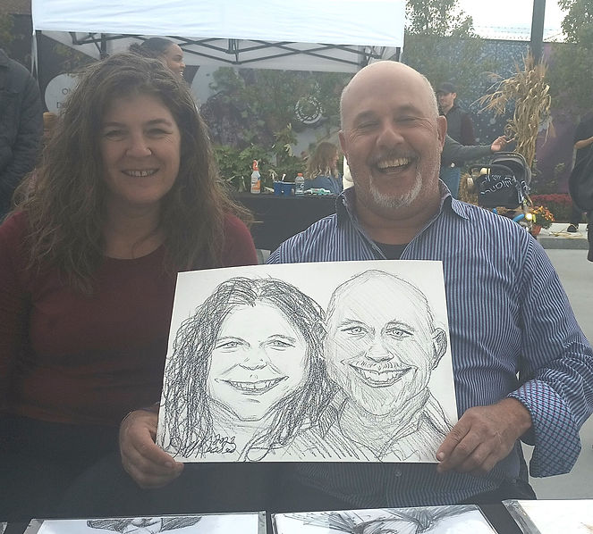 Couple posing with a custom caricature at a wedding reception.