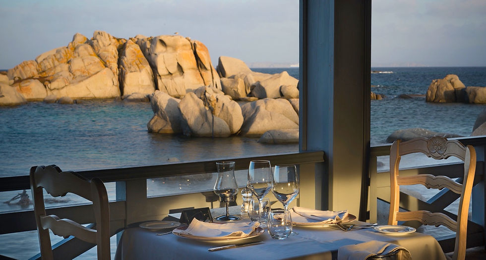 Exterior view of Restaurant Des Pêcheurs and the Shore Club on Cavallo Island, featuring typical pink granite rocks and turquoise Corsican waters.