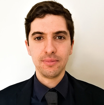 Oliver Fenghour wearing a dark jacket with burgundy tie with a plain white background behind him